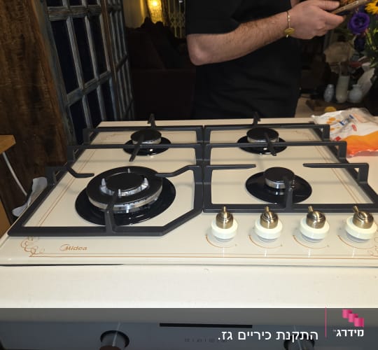 כיריים גז עם ארבעה מבערים ומתגים במטבח.